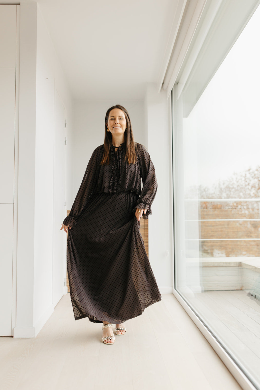 lang bruin kleedje met bolletjes en sierstrik aan de hals