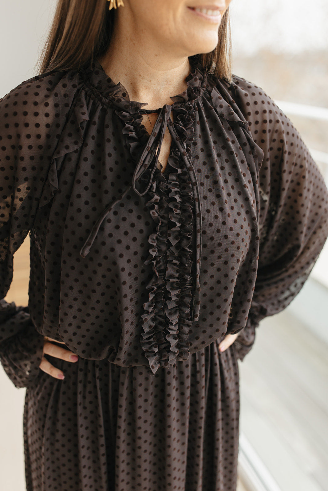 lang bruin kleedje met bolletjes en sierstrik aan de hals